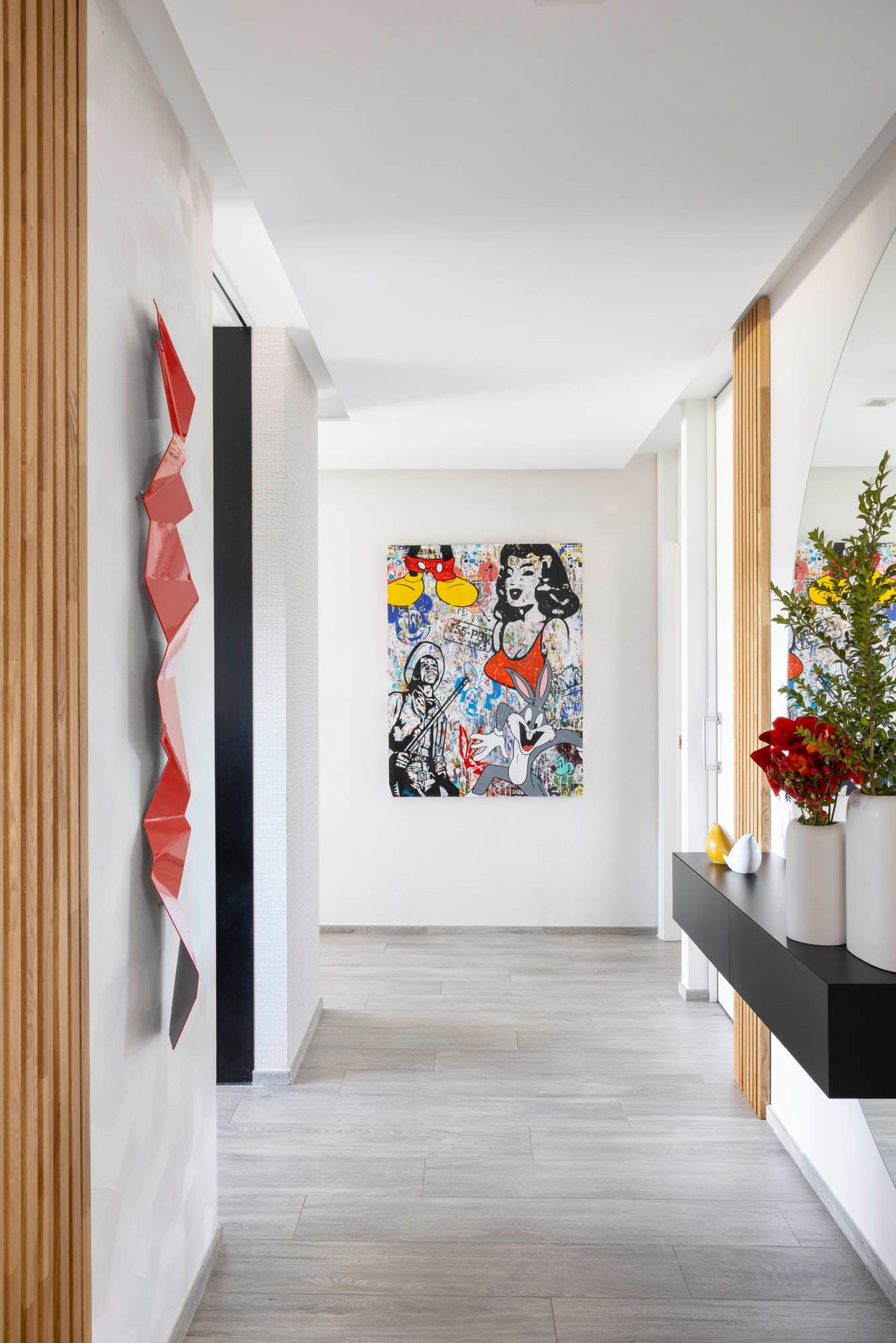 Recibidor con escultura roja, listones de madera y arte pop