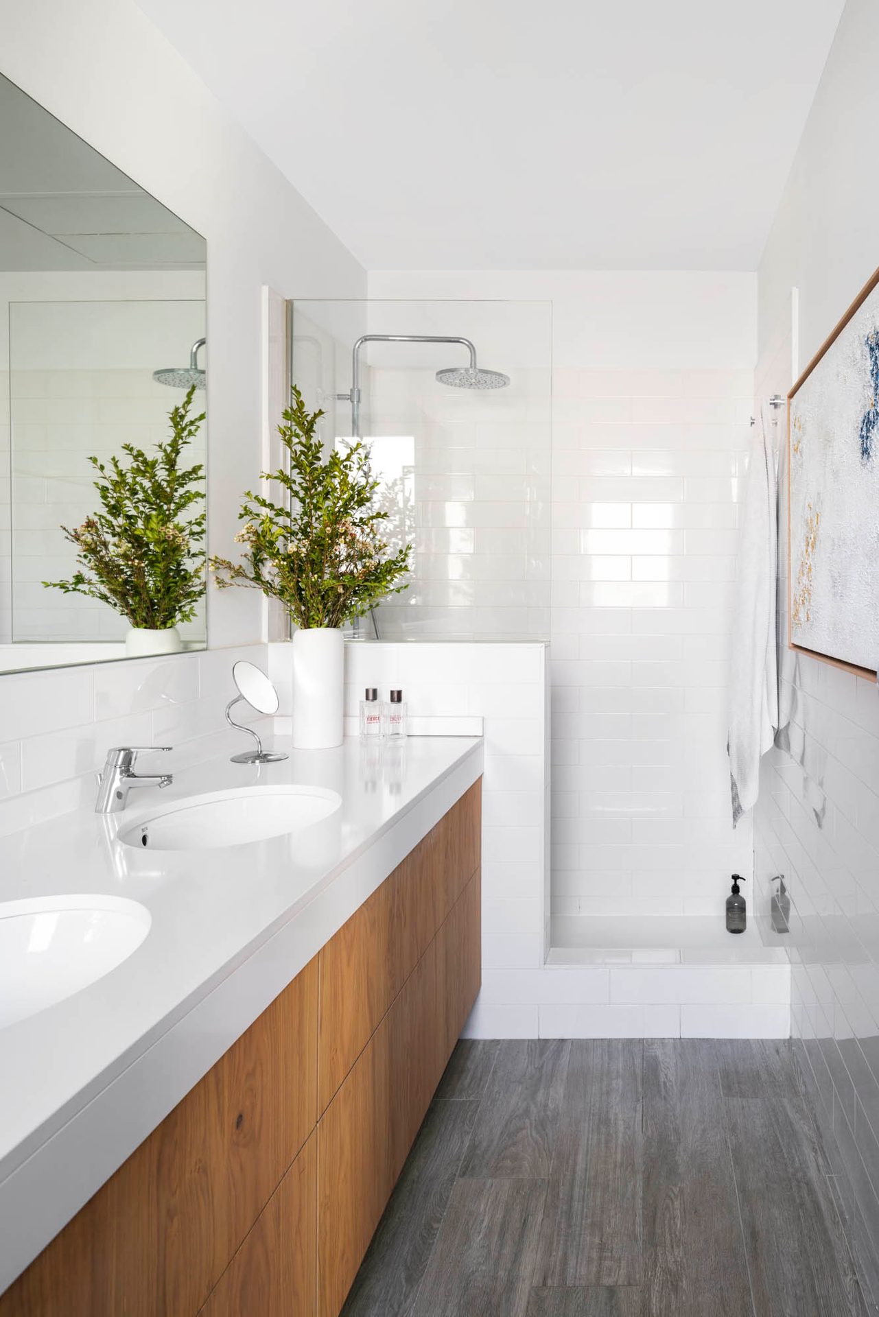 Baño con doble lavabo, mueble de madera y azulejo blanco
