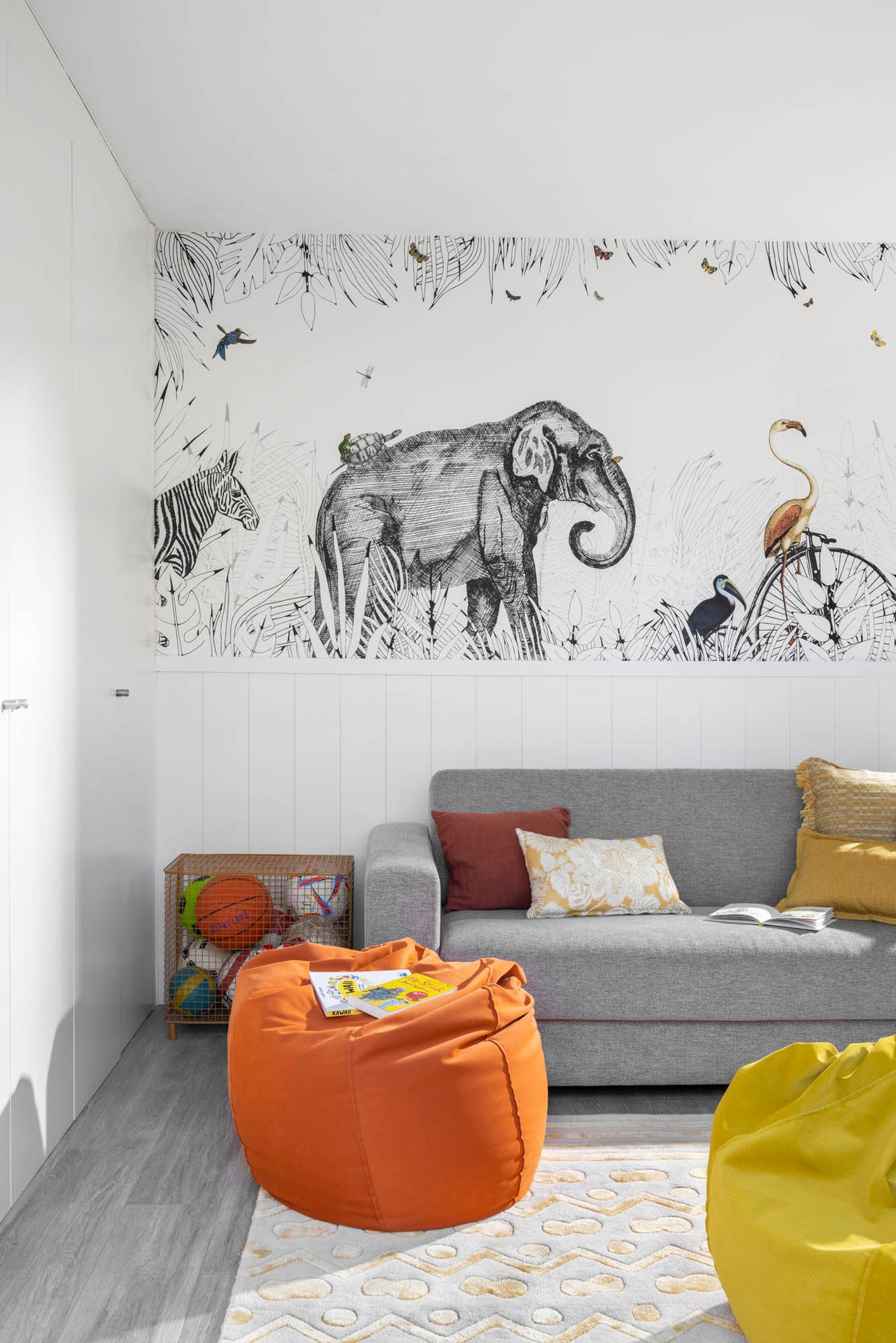 Sala de juegos infantil con mural de selva y pufs de colores