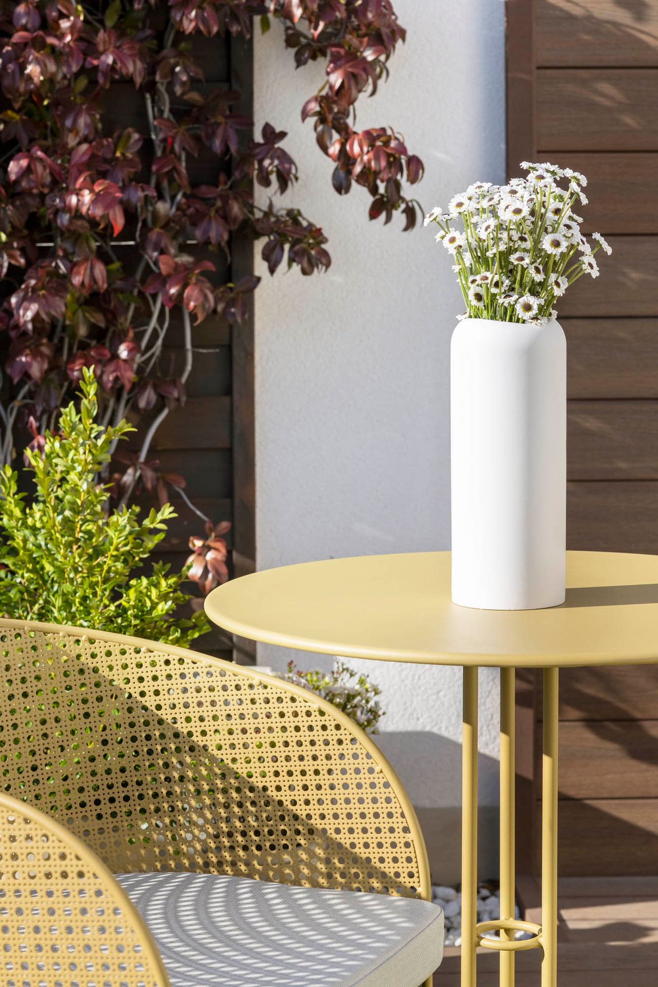 Mesa amarilla con jarrón blanco en la terraza