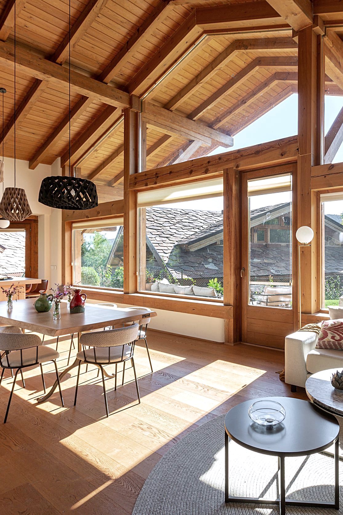 Salón y comedor bajo techo de vigas de madera con grandes ventanales en Sierra Norte de Madrid