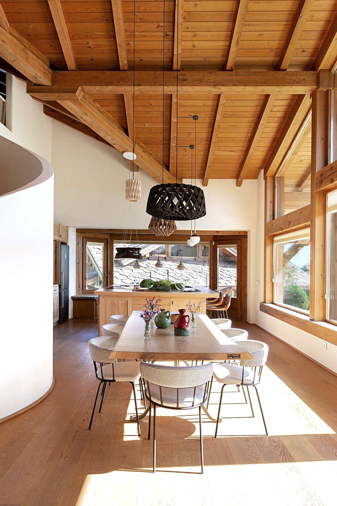 Comedor con mesa de madera y lámparas colgantes bajo cubierta de madera