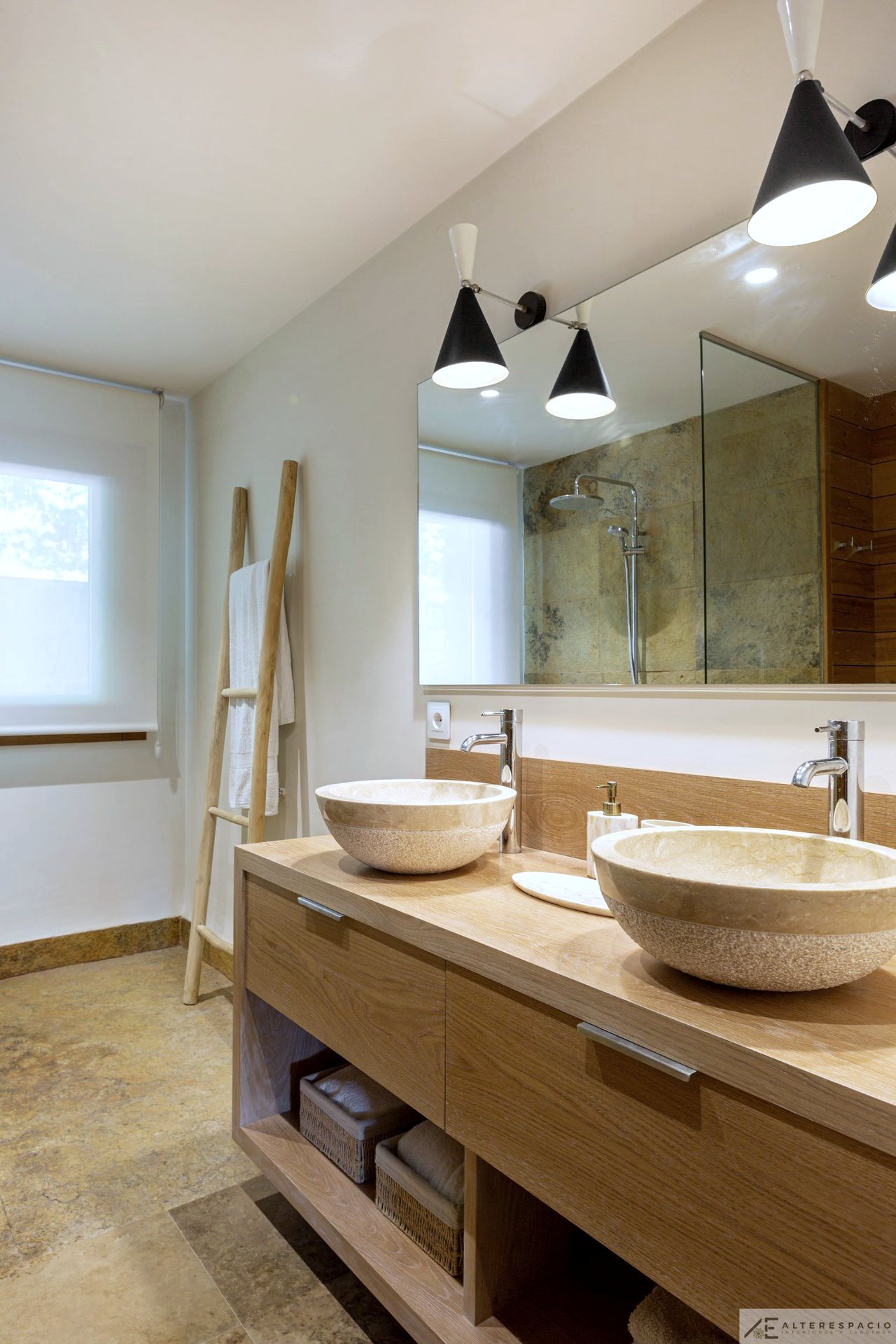 Baño con lavabos de piedra sobre mueble de madera