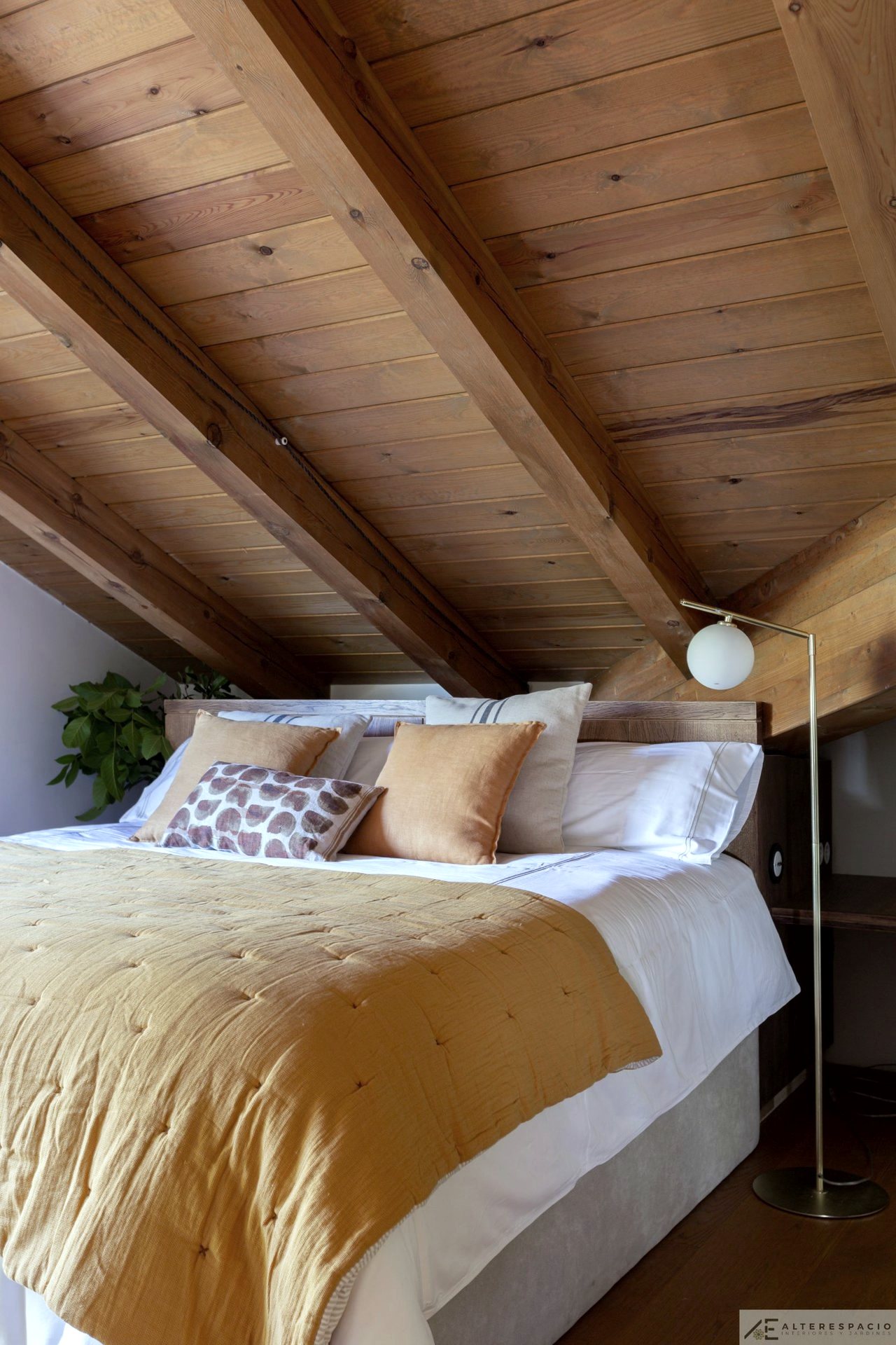 Dormitorio abuhardillado con vigas de madera vista