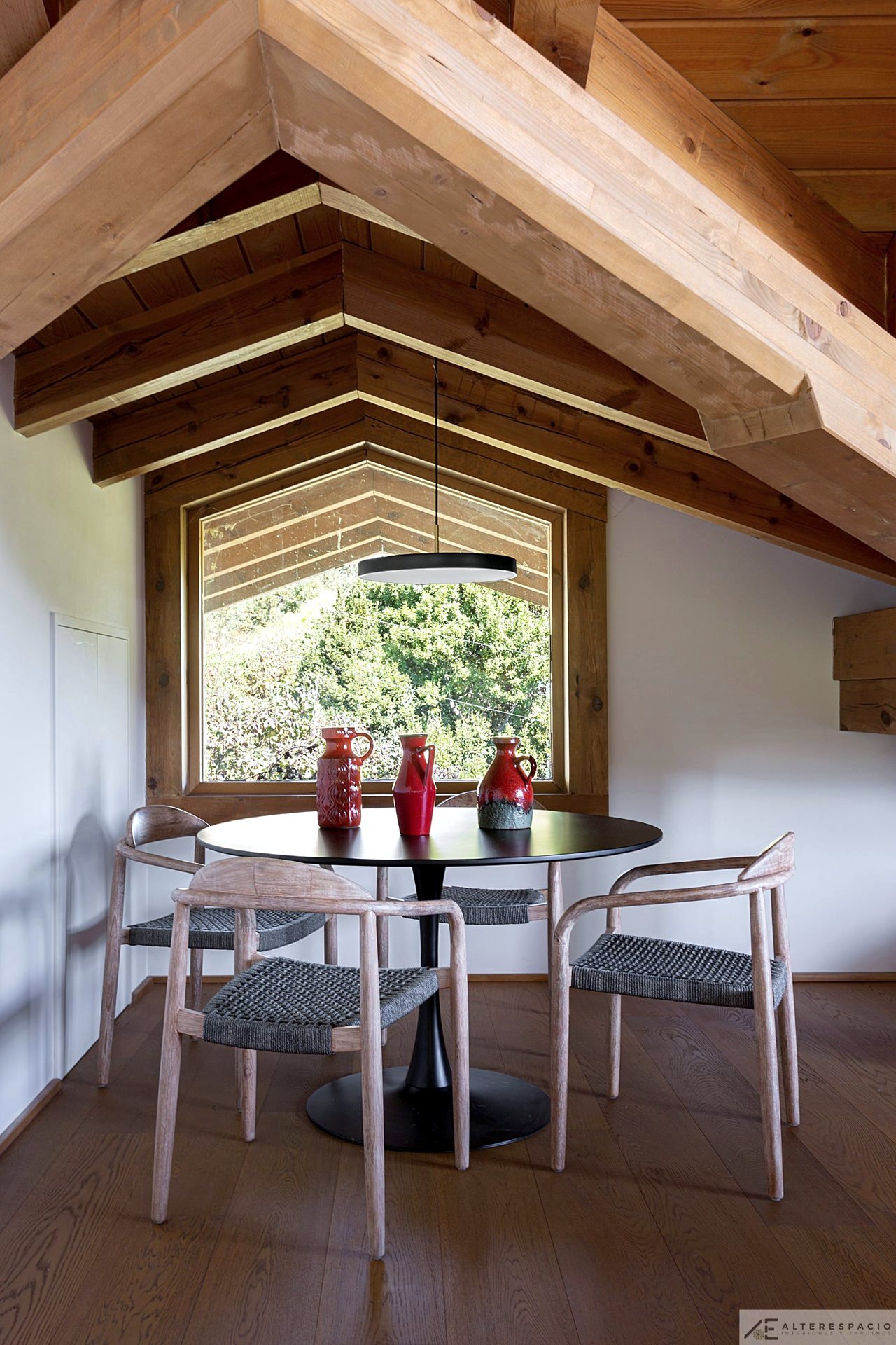 Rincón de comedor en la buhardilla junto a ventana triangular