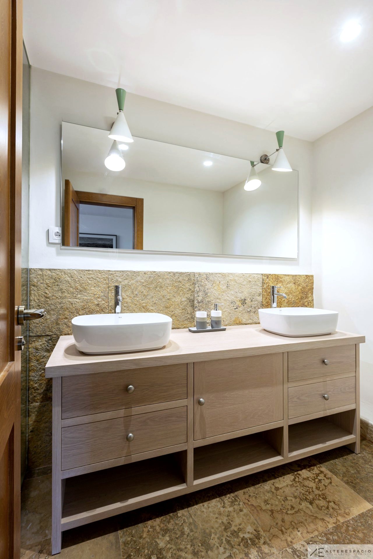 Baño con doble lavabo y pared de piedra