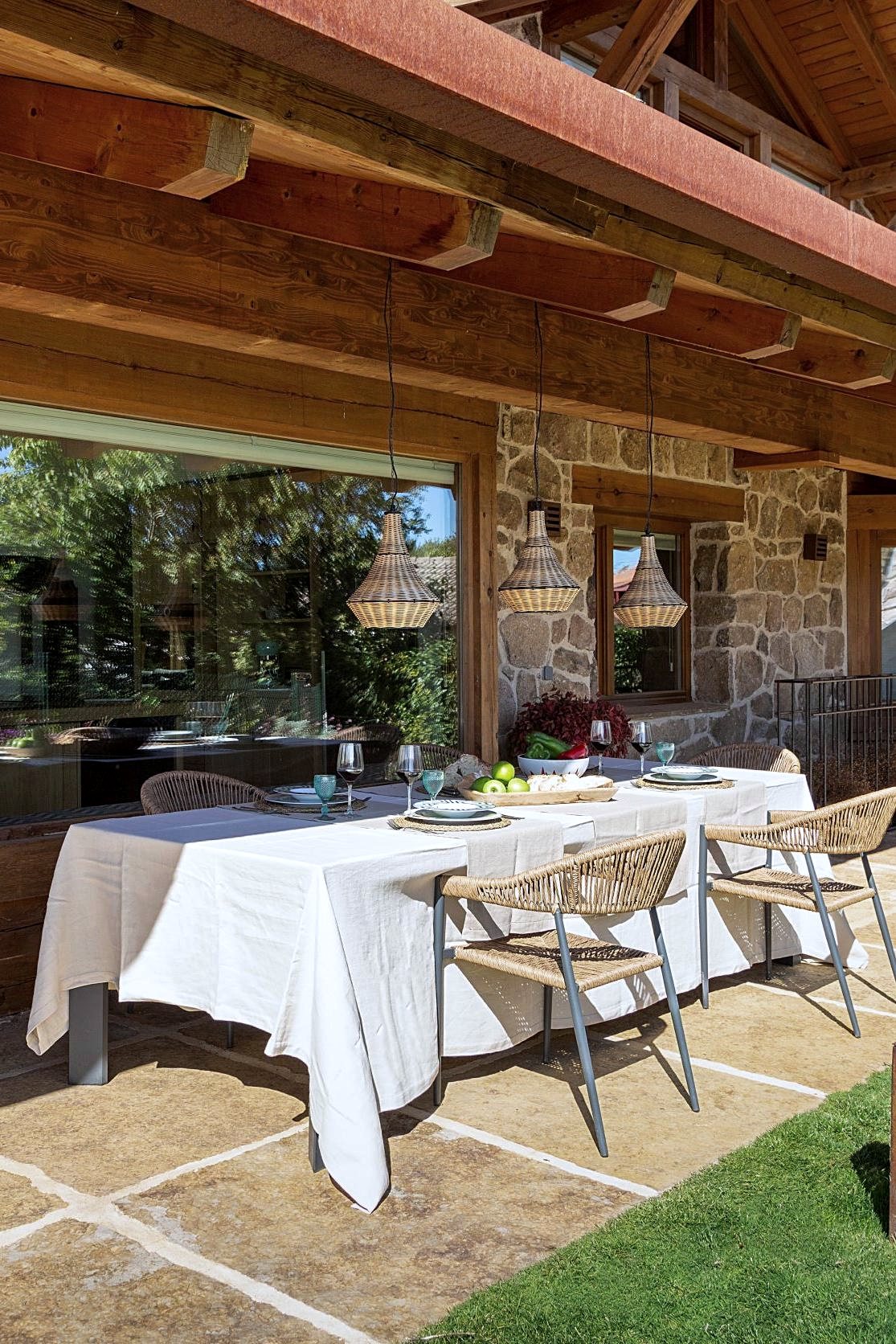 Comedor exterior en el porche con lámparas de fibra natural
